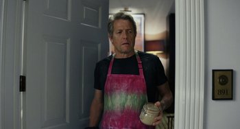 Movie still from “Glass Onion” (2022), directed by Rian Johnson – A man wearing an apron and holding a jar of peanut butter; Medium shot, Low angle
