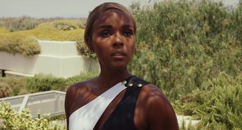 Movie still from “Glass Onion” (2022), directed by Rian Johnson – A woman in a black and white dress looking at the camera; Close Up shot, Over the shoulder angle