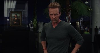 Movie still from “Glass Onion” (2022), directed by Rian Johnson – A man in a green shirt is standing in front of a palm tree; Medium shot, Over the shoulder angle