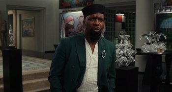 Movie still from “Glass Onion” (2022), directed by Rian Johnson – A man in a green suit and a black hat; Close Up shot, Low angle