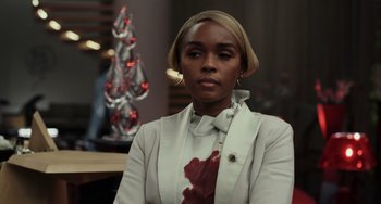 Movie still from “Glass Onion” (2022), directed by Rian Johnson – A woman in a white jacket with blood on her neck; Close Up shot, Over the shoulder angle