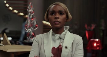 Movie still from “Glass Onion” (2022), directed by Rian Johnson – A woman in a white jacket with blood on her chest; Close Up shot, Over the shoulder angle