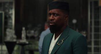 Movie still from “Glass Onion” (2022), directed by Rian Johnson – A man with a beard wearing a green jacket; Close Up shot, Over the shoulder angle