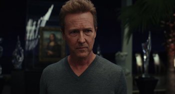 Movie still from “Glass Onion” (2022), directed by Rian Johnson – A person wearing a gray shirt; Close Up shot, Over the shoulder angle