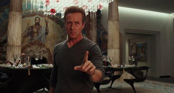 Movie still from “Glass Onion” (2022), directed by Rian Johnson – A man in a gray shirt is pointing his finger at the camera; Medium shot, Low angle