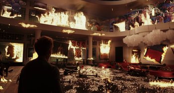 Movie still from “Glass Onion” (2022), directed by Rian Johnson – A man standing in front of a building on fire; Extreme Wide shot, High angle