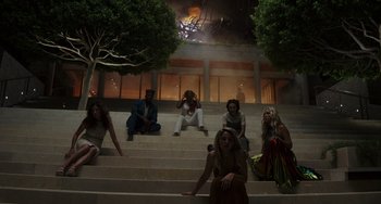 Movie still from “Glass Onion” (2022), directed by Rian Johnson – A group of people sitting on top of a set of stairs; Wide shot, Overhead angle