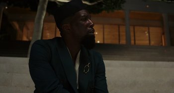 Movie still from “Glass Onion” (2022), directed by Rian Johnson – A man with a beard wearing a suit and tie; Close Up shot, Low angle