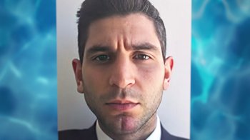 Movie still from “God Forbid” (2022), directed by Billy Corben – A person wearing a suit and tie; Extreme Close Up shot, High angle
