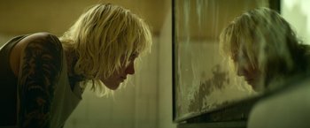 Movie still from “God Is a Bullet” (2023), directed by Nick Cassavetes – A woman looking at a fish tank in a room; Close Up shot, Low angle