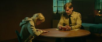 Movie still from “God Is a Bullet” (2023), directed by Nick Cassavetes – A man and a woman sitting at a wooden table; Medium shot, Over the shoulder angle