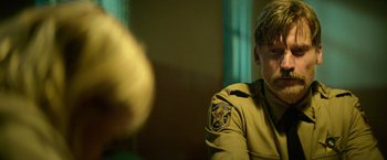 Movie still from “God Is a Bullet” (2023), directed by Nick Cassavetes – A man in a uniform sitting in front of a window; Close Up shot, Over the shoulder angle