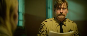 Movie still from “God Is a Bullet” (2023), directed by Nick Cassavetes – A person wearing a jacket and a tie; Close Up shot, Over the shoulder angle