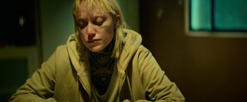 Movie still from “God Is a Bullet” (2023), directed by Nick Cassavetes – A woman with a tattoo on her neck is sitting in a room; Close Up shot, High angle