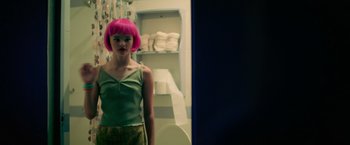 Movie still from “God Is a Bullet” (2023), directed by Nick Cassavetes – A woman with pink hair standing in a bathroom; Medium shot, Over the shoulder angle