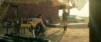 Movie still from “God Is a Bullet” (2023), directed by Nick Cassavetes – A woman standing in front of two men in chairs; Wide shot, Over the shoulder angle