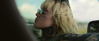 Movie still from “God Is a Bullet” (2023), directed by Nick Cassavetes – A woman with a tattoo on her face and glasses; Close Up shot, Low angle