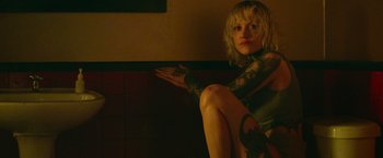 Movie still from “God Is a Bullet” (2023), directed by Nick Cassavetes – A woman sitting on the ground with her hand extended out; Close Up shot, Low angle