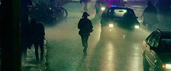 Movie still from “God Is a Bullet” (2023), directed by Nick Cassavetes – A person walking down a street in the rain; Extreme Wide shot, High angle