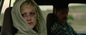 Movie still from “God Is a Bullet” (2023), directed by Nick Cassavetes – A young woman in a car with a man in the background; Close Up shot, Over the shoulder angle