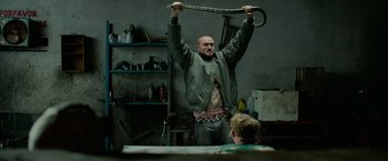 Movie still from “God Is a Bullet” (2023), directed by Nick Cassavetes – A man holding up a large snake in a garage; Medium shot, Low angle