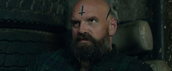 Movie still from “God Is a Bullet” (2023), directed by Nick Cassavetes – A bald man with a cross on his forehead; Close Up shot, Over the shoulder angle