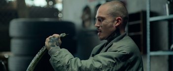 Movie still from “God Is a Bullet” (2023), directed by Nick Cassavetes – A man with a tattoo on his face holding a knife; Close Up shot, Over the shoulder angle