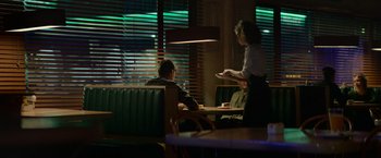 Movie still from “God Is a Bullet” (2023), directed by Nick Cassavetes – A woman is serving a plate to two people at a restaurant; Wide shot, Over the shoulder angle