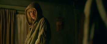 Movie still from “God Is a Bullet” (2023), directed by Nick Cassavetes – A man in a hooded jacket standing in a dark room; Medium shot, Over the shoulder angle