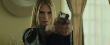 Movie still from “God Is a Bullet” (2023), directed by Nick Cassavetes – A woman holding a gun in a room; Close Up shot, Low angle
