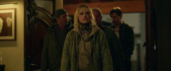 Movie still from “God Is a Bullet” (2023), directed by Nick Cassavetes – A woman in a green jacket standing in front of a group of men; Medium shot, Over the shoulder angle