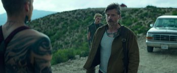 Movie still from “God Is a Bullet” (2023), directed by Nick Cassavetes – A man in a brown jacket is walking on a hill; Medium shot, Over the shoulder angle