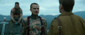 Movie still from “God Is a Bullet” (2023), directed by Nick Cassavetes – A man with tattoos on his chest and shoulders; Medium shot, Over the shoulder angle