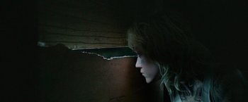 Movie still from “God Is a Bullet” (2023), directed by Nick Cassavetes – A woman looking out a window in a dark room; Close Up shot, Low angle