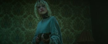 Movie still from “God Is a Bullet” (2023), directed by Nick Cassavetes – A woman holding a cell phone while standing in front of a wall; Medium shot, Low angle