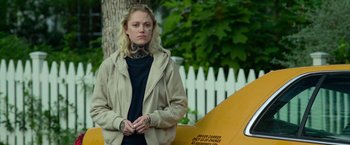 Movie still from “God Is a Bullet” (2023), directed by Nick Cassavetes – A woman standing next to a surfboard in front of a fence; Medium shot, Over the shoulder angle