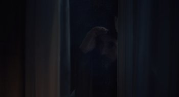 Movie still from “God's Country” (2022), directed by Julian Higgins – A man standing in a dark room looking out of a window; Extreme Close Up shot, Over the shoulder angle