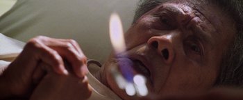 Movie still from “Godzilla” (1998), directed by Roland Emmerich – An older man is holding something in his mouth; Extreme Close Up shot, Overhead angle