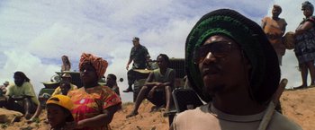 Movie still from “Godzilla” (1998), directed by Roland Emmerich – A group of people sitting on top of a dirt field; Medium shot, Low angle