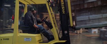 Movie still from “Godzilla” (1998), directed by Roland Emmerich – A man sitting on a yellow fork lift truck; Wide shot, Low angle