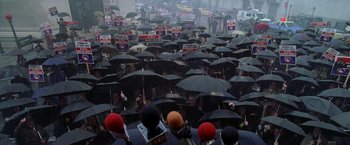 Movie still from “Godzilla” (1998), directed by Roland Emmerich – A large group of people holding umbrellas over their heads; Extreme Wide shot, High angle