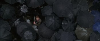 Movie still from “Godzilla” (1998), directed by Roland Emmerich – A man sitting in the middle of an umbrella filled room; Wide shot, Overhead angle