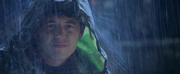 Movie still from “Godzilla” (1998), directed by Roland Emmerich – A young man in a raincoat is under an umbrella in the pouring rain; Close Up shot, Low angle