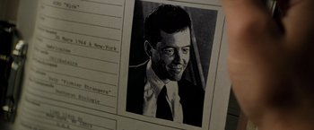 Movie still from “Godzilla” (1998), directed by Roland Emmerich – A black and white photo of a man in a suit and tie; Extreme Close Up shot, Overhead angle