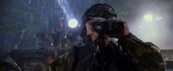 Movie still from “Godzilla” (1998), directed by Roland Emmerich – A man in a raincoat looking through binoculars in the rain; Close Up shot, Over the shoulder angle