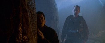 Movie still from “Godzilla” (1998), directed by Roland Emmerich – A man standing in front of a wall in a dark room; Medium shot, Low angle