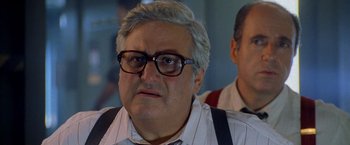 Movie still from “Godzilla” (1998), directed by Roland Emmerich – An older man wearing glasses and wearing suspenders; Close Up shot, Low angle