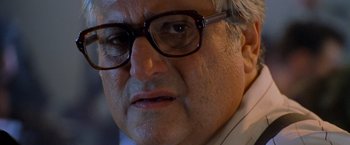 Movie still from “Godzilla” (1998), directed by Roland Emmerich – An older man wearing glasses looking at the camera; Close Up shot, Over the shoulder angle