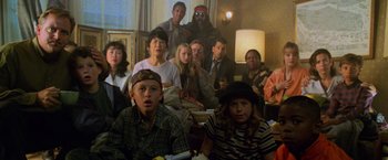 Movie still from “Godzilla” (1998), directed by Roland Emmerich – A group of people sitting in a living room together; Medium shot, High angle
