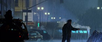 Movie still from “Godzilla” (1998), directed by Roland Emmerich – A man walking down a street in the rain; Wide shot, Low angle